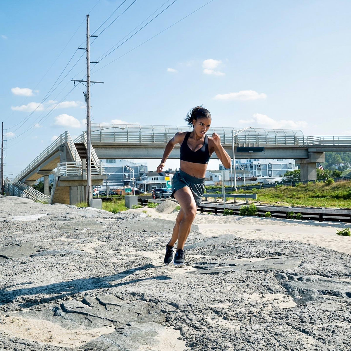 Coach Brittany Watts running in workout clothes next to a highway.